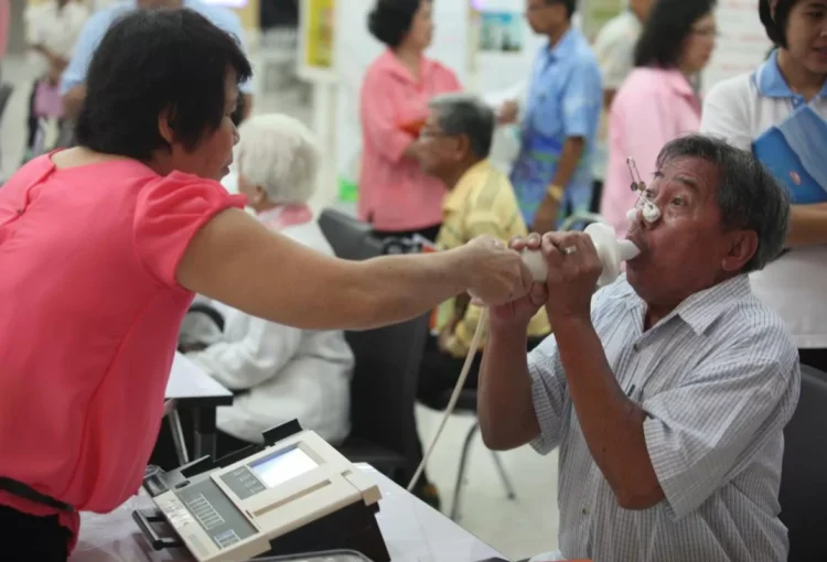 An elderly man breathes into a device to test his lungs at an event to educate the public about emphysema at Ramathibodi Hospital on Nov 12, 2012. PATTANAPONG HIRUNARD